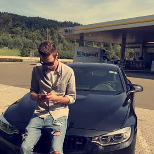 Riccardo Göderle, Autor des Dropshipping Kurses Ecomination, sitzt mit Smartphone auf einem Auto