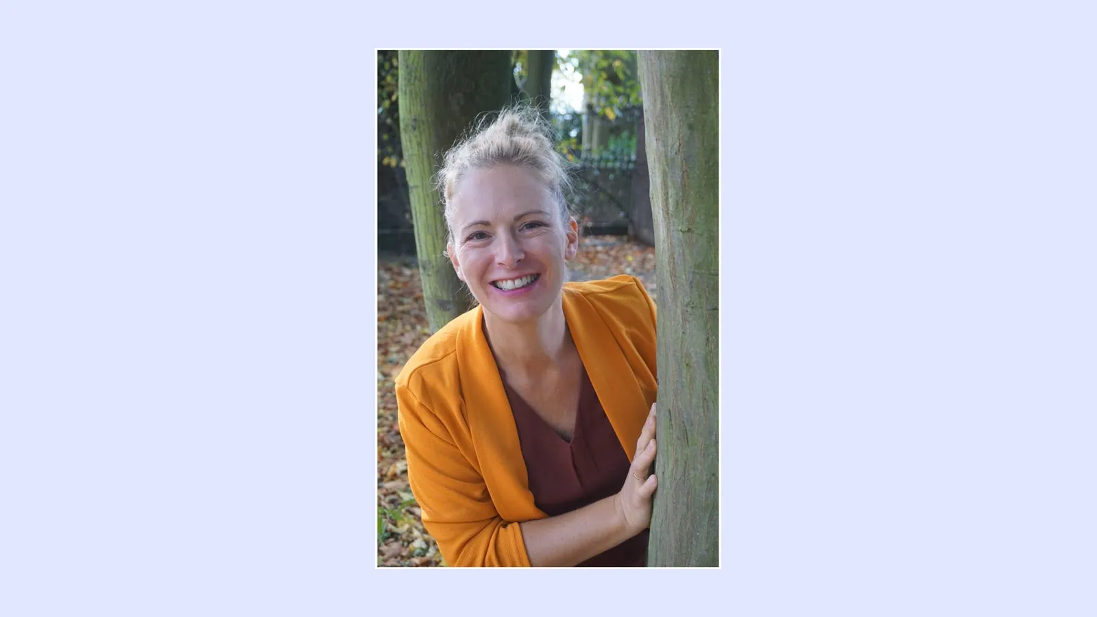 Carina Mathes, Autorin des Schulfachs Glückskompetenz, lächelnd an einem Baum im Herbstlaub