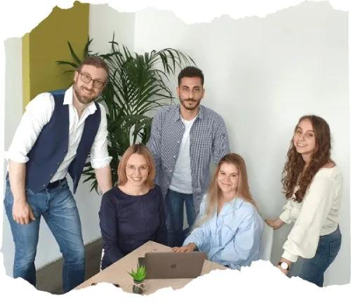 Das fünfköpfige Szenario-Zwei Team gemeinsam an einem Tisch mit Laptop