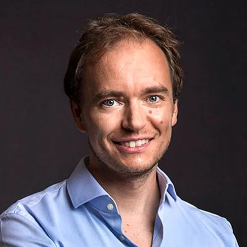 Porträt von Thomas Klußmann im hellblauen Hemd vor dunklem Hintergrund