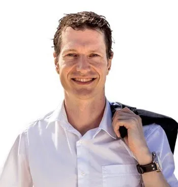 Thorsten Wittmann, Autor des Kurses Crash - Chaos - CHANCE, lächelnd im weißen Hemd mit Sakko über der Schulter