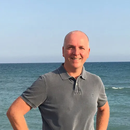 Torsten Jaeger im grauen Poloshirt lächelnd am Meer