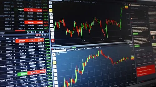 Mehrere Monitore mit Candlestick-Charts und Kurslisten als Symbolbild für das Top Trader Programm