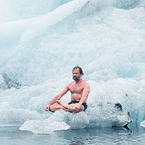 Wim Hof sitzt im Schneidersitz mit nacktem Oberkörper auf einem Eisberg im Wasser