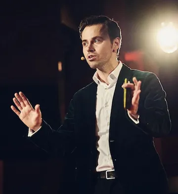 Wladislaw Jachtchenko spricht gestikulierend mit Headset-Mikrofon auf einer Bühne